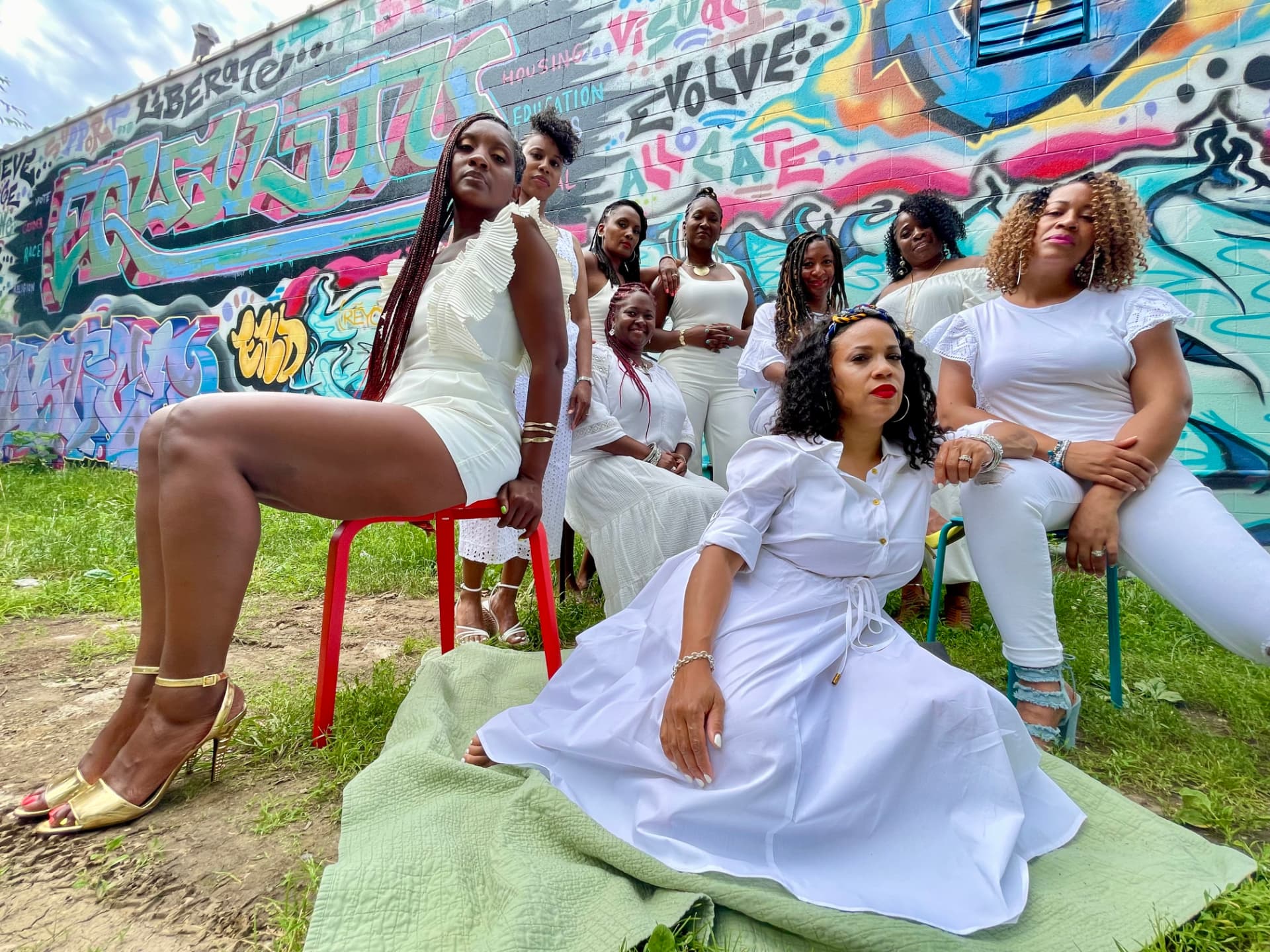 A group of women dressed in white posing in front of a colorful graffiti wall
