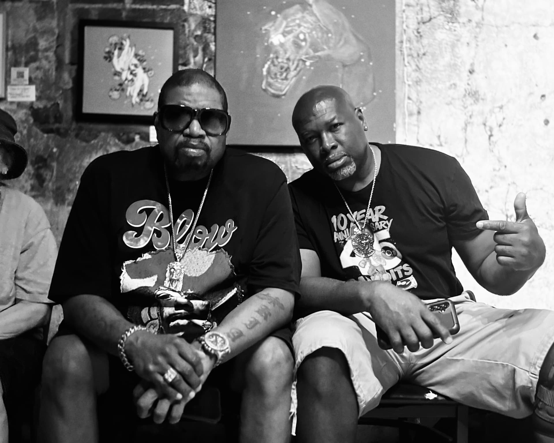 Two men in graphic T-shirts seated together at an event